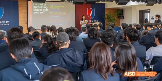 A group of Ealing International School students attending a lecture in a large room.