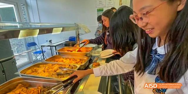 Ealing International School students are serving themselves from a buffet in a cafeteria.