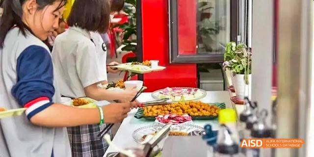 Ealing International School students are at a festive buffet table with various dishes.