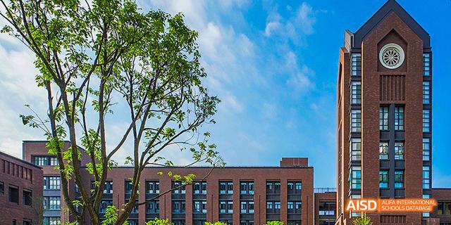 A view of a brick school building with a large tree and a bright blue sky at Fuzhou Concord College of Sino-Canada.