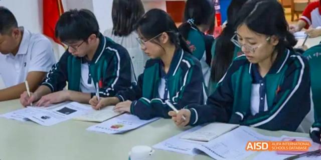 Two students sitting at a desk and writing in notebooks in a classroom at Fuzhou Concord College of Sino-Canada.