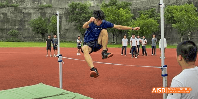 An athlete in mid-air during a long jump competition on a red track at Fuzhou Concord College of Sino-Canada.