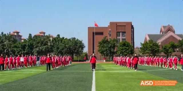Students in red uniforms standing in formation on a green field at Fuzhou Concord College of Sino-Canada.