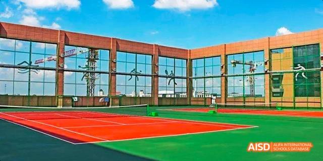 The exterior of a building with glass windows overlooking a tennis court at Fuzhou Concord College of Sino-Canada.
