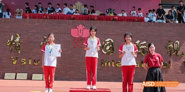 A female student receiving an award on a podium during a ceremony at Fuzhou Concord College of Sino-Canada.