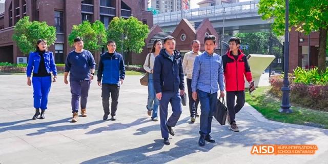 A group of people, including two men in suits, walking outdoors on the campus of Fuzhou Concord College of Sino-Canada.