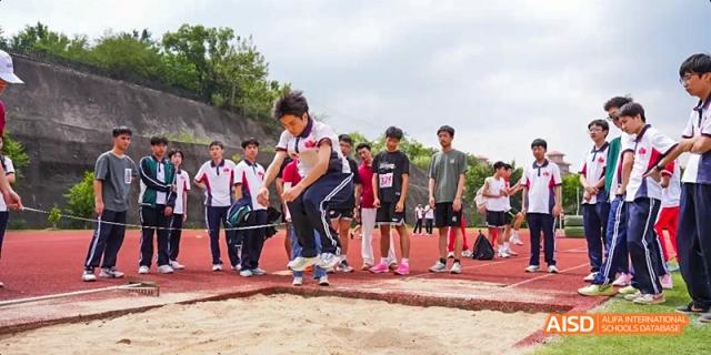 Athletes competing in a long jump event on a dirt field at Fuzhou Concord College of Sino-Canada.