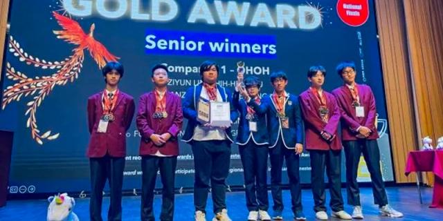 A woman speaking into a microphone while standing with a group of students and holding awards at Fuzhou Concord College of Sino-Canada.