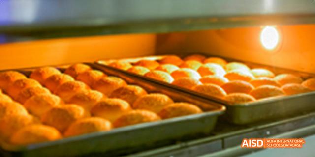Fuzhou Concord College of Sino-Canada - A close-up view of freshly baked, golden-brown buns arranged on a baking sheet inside an oven.