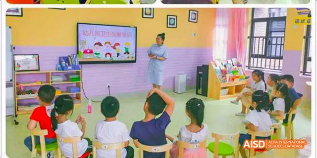 Fuzhou Concord College of Sino-Canada - A teacher in a light blue uniform is standing in front of a smart board, teaching a class of young students who are sitting in chairs.
