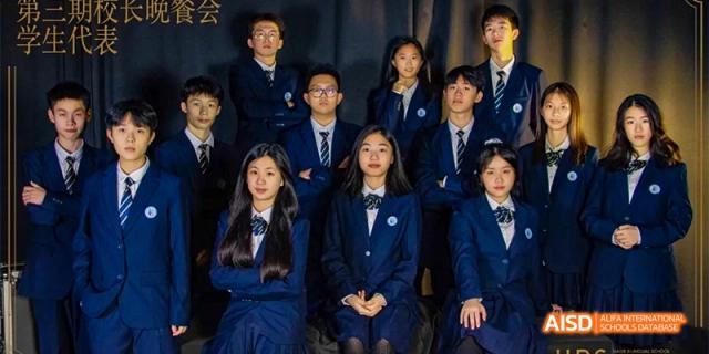 A close-up of a small group of students from HAIDE Bilingual School Dongguan in their school uniforms, sitting and posing for a photo.