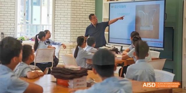 A teacher from HAIDE Bilingual School Dongguan instructing students at the front of a classroom.