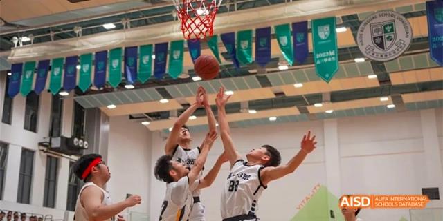 A dynamic photo of students from HAIDE Bilingual School Dongguan competing in a basketball game, reaching for a loose ball.