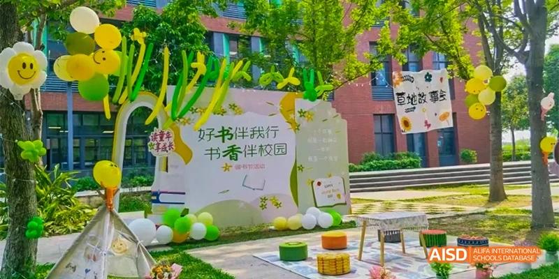 An outdoor display at HAIDE Bilingual School Dongguan with green and yellow balloons and a sign that reads "HAODE Campus" in Chinese, which translates to "Good book accompanies me".