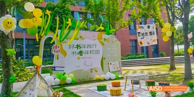 An outdoor display at HAIDE Bilingual School Dongguan with green and yellow balloons and a sign that reads "HAODE Campus" in Chinese, which translates to "Good book accompanies me".