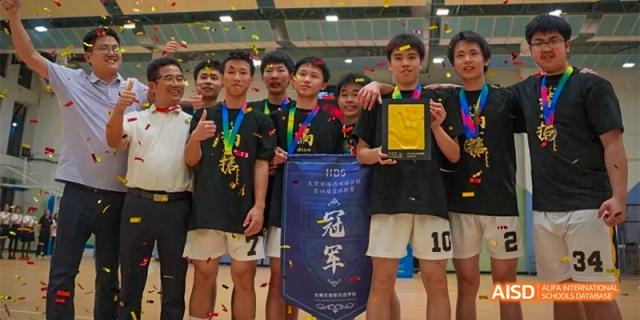 A group of male students from HAIDE Bilingual School Dongguan posing with a trophy and medals after winning a basketball championship.