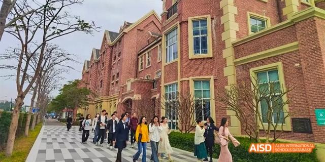 Students and teachers from HAIDE Bilingual School Dongguan walking outside a red-brick school building.