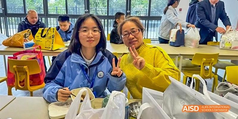 Students from HAIDE Bilingual School Dongguan smiling and posing for a group photo while holding food from the cafeteria.