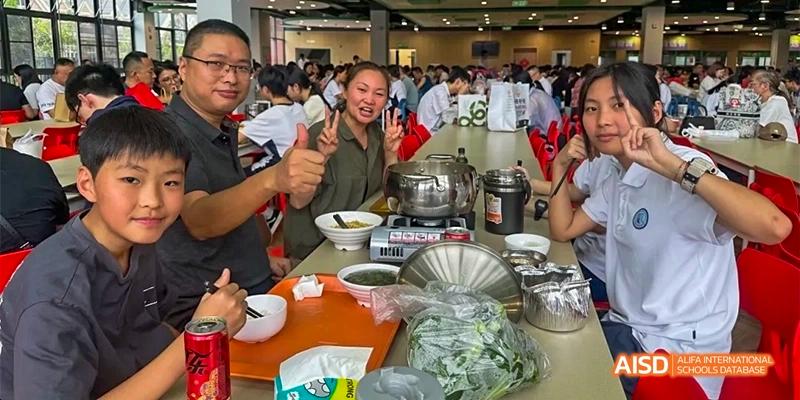 Students from HAIDE Bilingual School Dongguan eating hot pot at a table, smiling and enjoying a meal together.