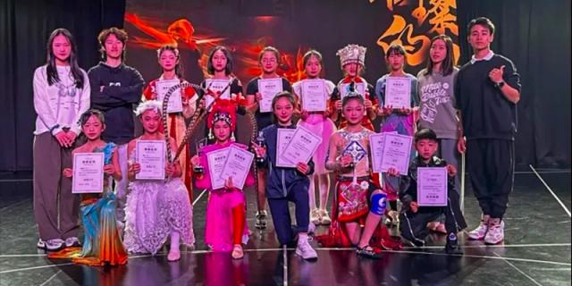 Young students from HAIDE Bilingual School Dongguan posing on stage with certificates and awards after a performance.