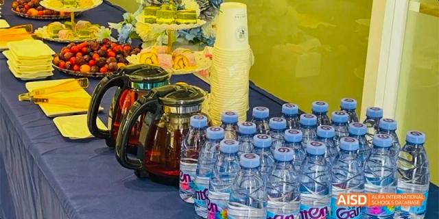 A refreshment station with bottles of water, jugs of juice, and other beverages at an event at HAIDE Bilingual School Dongguan.