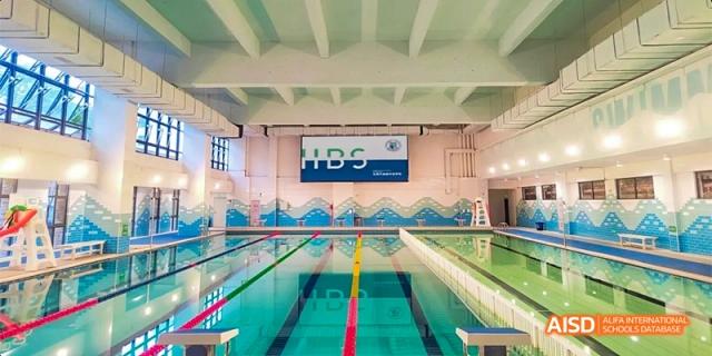 The indoor swimming pool at HAIDE Bilingual School Dongguan, showing multiple lanes with lane markers and starting blocks.