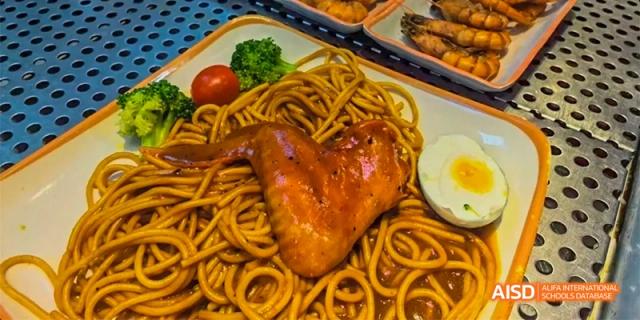 A dish of spaghetti with a chicken wing on top, served on a plate in the cafeteria at HAIDE Bilingual School Dongguan.