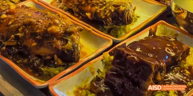 A close-up shot of cooked meat and potatoes on a plate in the cafeteria at HAIDE Bilingual School Dongguan.