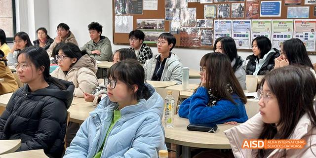 Hangzhou Foreign Languages School students sitting at desks, engaged in a conversation or group discussion in a classroom setting.