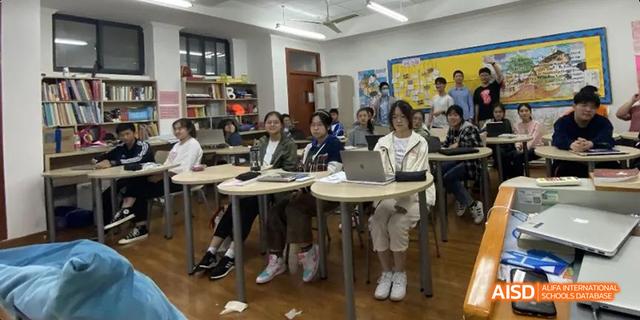 A small group of Hangzhou Foreign Languages School students sitting around desks, participating in a focused class activity or discussion.