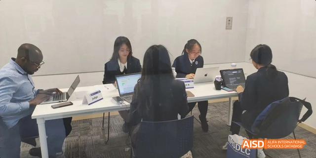 Hangzhou Foreign Languages School students or staff working on laptops and papers during a focused study or administrative session.