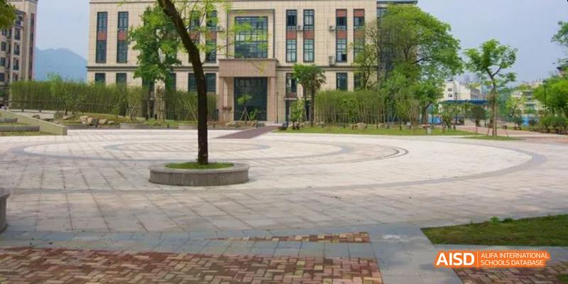 The exterior view of a building at Hangzhou Foreign Languages School, showcasing the manicured campus grounds, paved walkways, and trees.