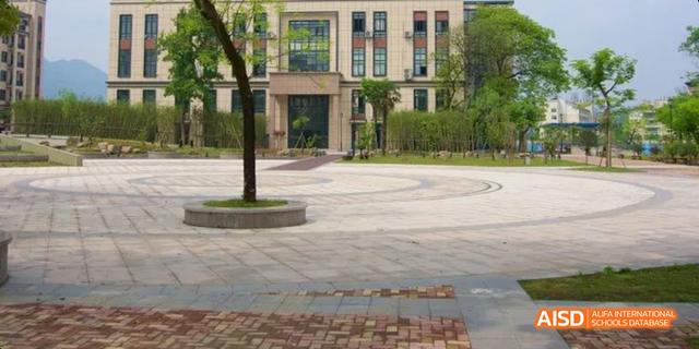 The exterior view of a building at Hangzhou Foreign Languages School, showcasing the manicured campus grounds, paved walkways, and trees.