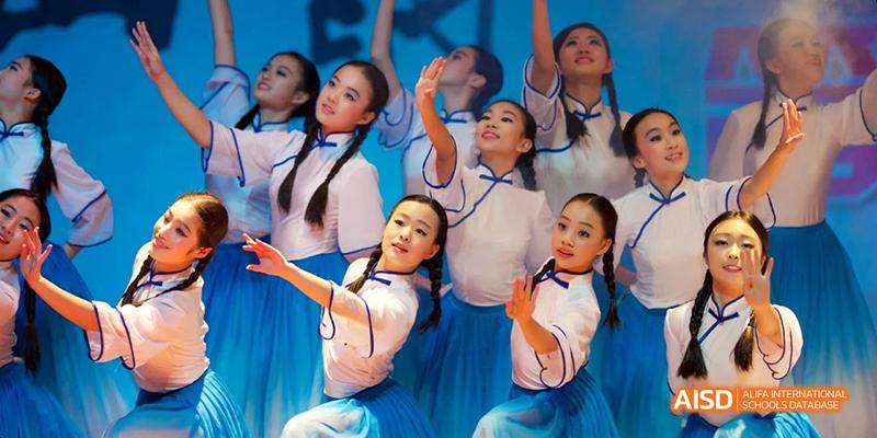 Female students from Hangzhou Foreign Languages School performing a traditional or contemporary dance in bright blue and white costumes on a stage.