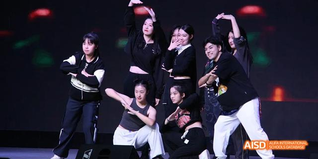Hangzhou Foreign Languages School students performing a dynamic, modern dance routine on a stage, dressed in black and white attire.
