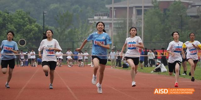Two female students from Hangzhou Foreign Languages School running on the track, smiling as they participate in a running event.