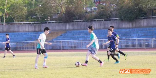 Hangzhou Foreign Languages School students playing a game of soccer (football) on an outdoor field.