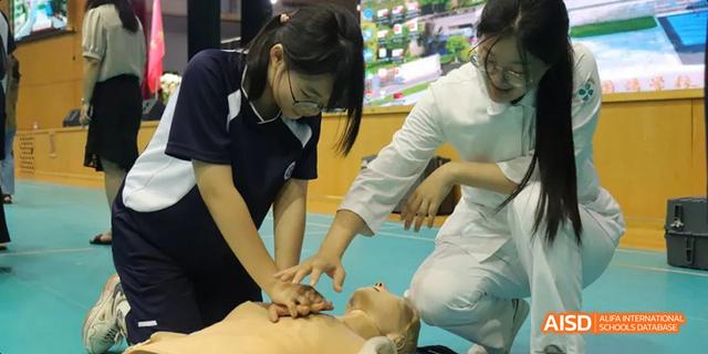 Hangzhou Foreign Languages School students practicing CPR (Cardiopulmonary Resuscitation) techniques on a training mannequin during a health and safety class.