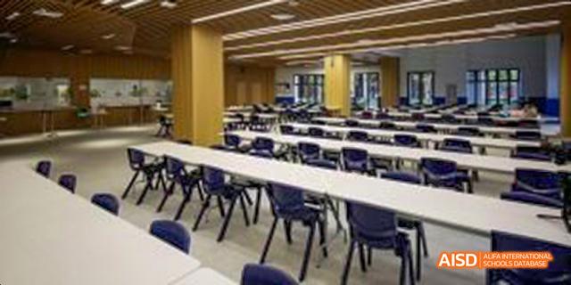 An empty classroom or study hall at Harrow LiDe School Haikou with desks and chairs.