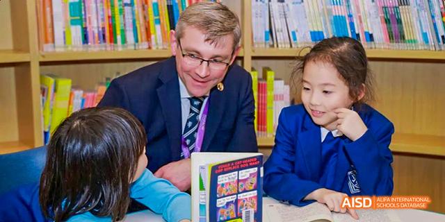 A teacher from Harrow LiDe School Haikou is reading a book to a young student.