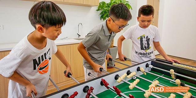 A male student from Harrow LiDe School Haikou plays a game of foosball in a recreational area.