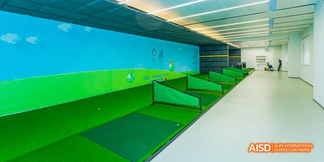 An indoor golf practice area at Harrow LiDe School Haikou with a screen for a golf simulator.
