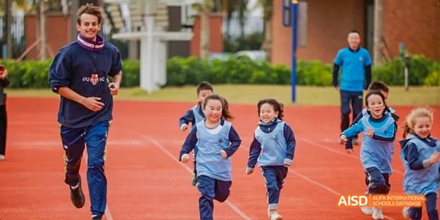 A group of young students from Harrow LiDe School Haikou are running on a track during a sports day.