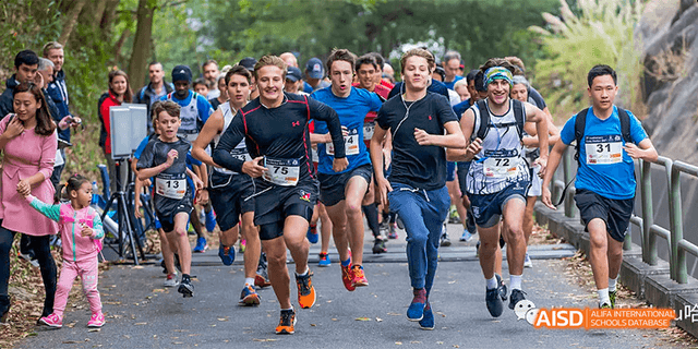 A group of male runners from Harrow LiDe School Haikou smile as they run together in an event.