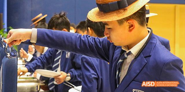 A male student from Harrow LiDe School Haikou is receiving a medal from a teacher or coach.