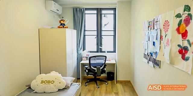 A desk with a chair in a student dormitory room at Harrow LiDe School Haikou, with a window in the background.