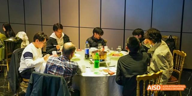 A group of people, possibly students and teachers from Harrow LiDe School Haikou, are seated around a table for a meal.