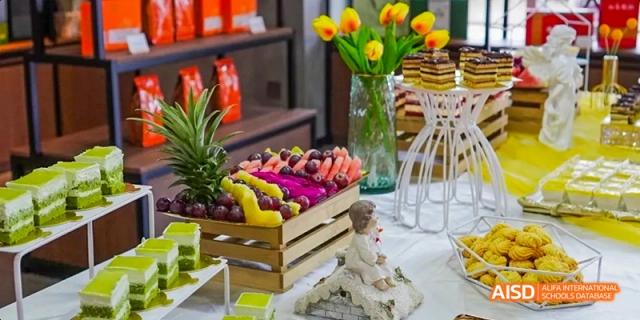 A display of fruits, including grapes, and a doll on a table at an event hosted by Harrow LiDe School Haikou.