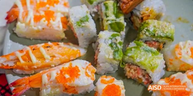 A tray of sushi rolls with various toppings and fillings is displayed at an event at Harrow LiDe School Haikou.