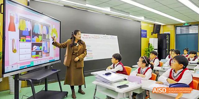 A teacher from Hefei Thomas School helps a student with a math problem at a whiteboard.